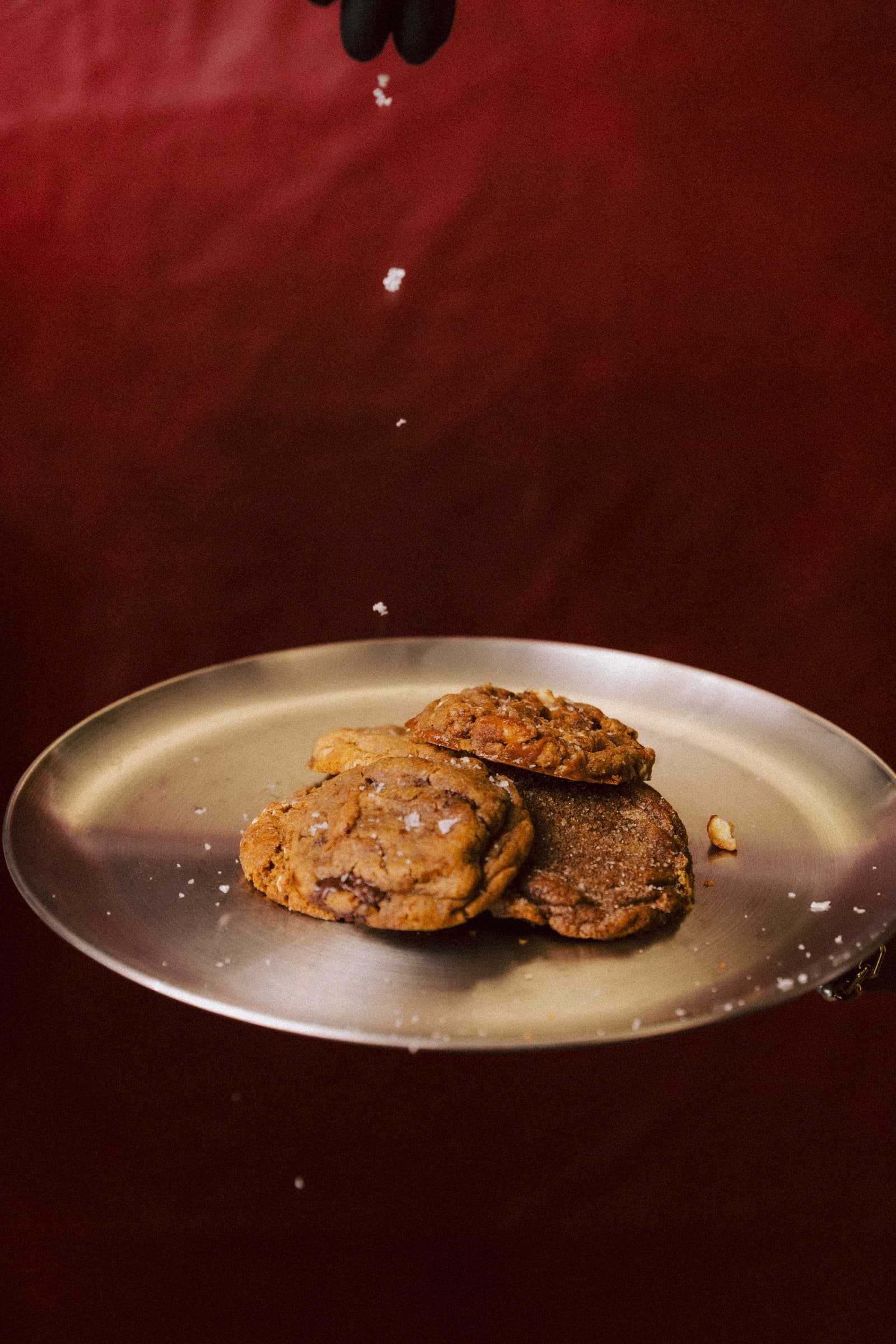 Flaky salt falling onto a silver tray of cookies