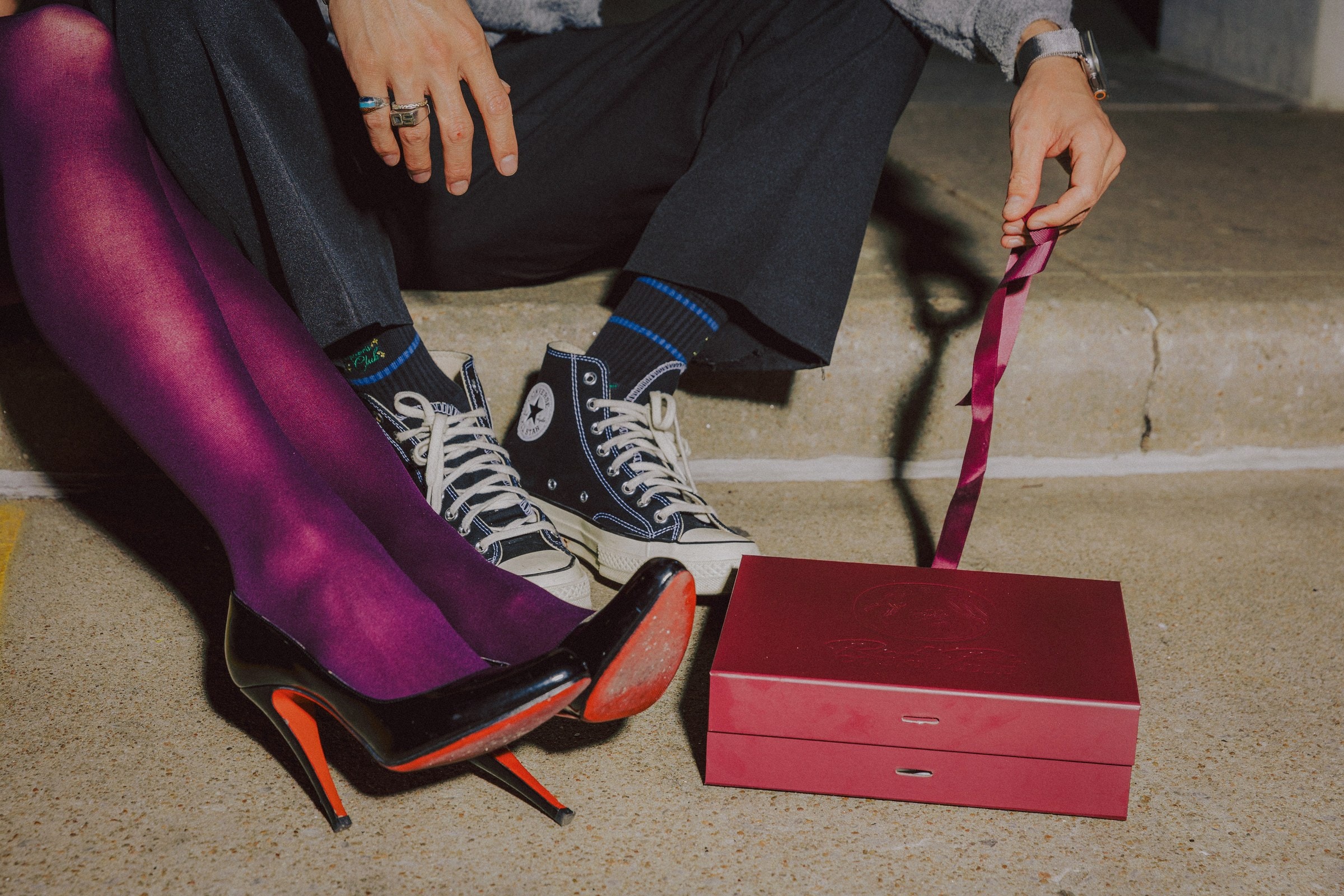 A ribboned Ring & Robe box on the curb between two pairs of shoes