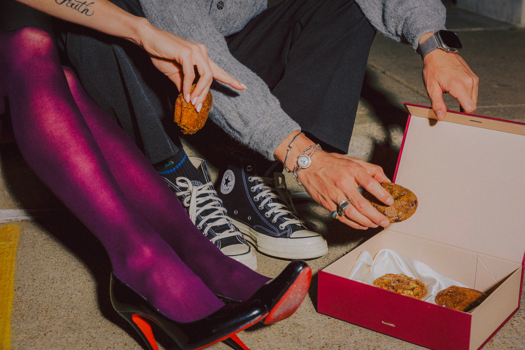 Friends on a curb sharing cookies from an open Ring & Robe box